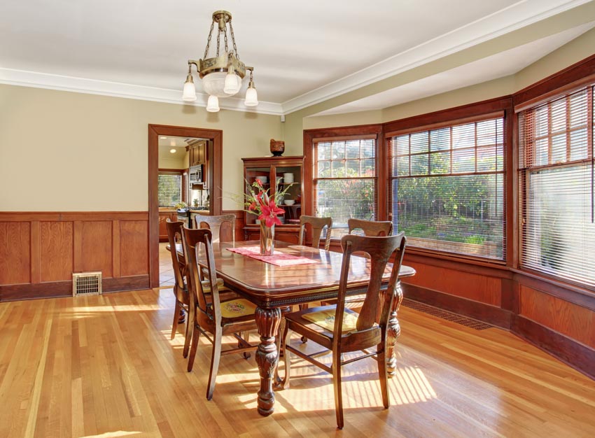 Spacious dining room with table, chairs, wainscoting, wood floor, and windows