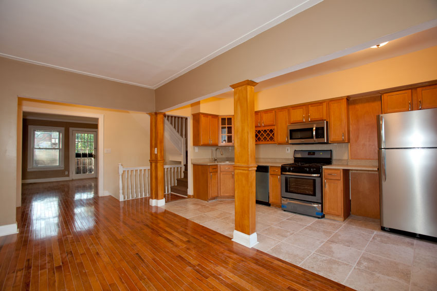 Spacious kitchen with honey oak cabinets, wood floor, pillars, oven, and backsplash
