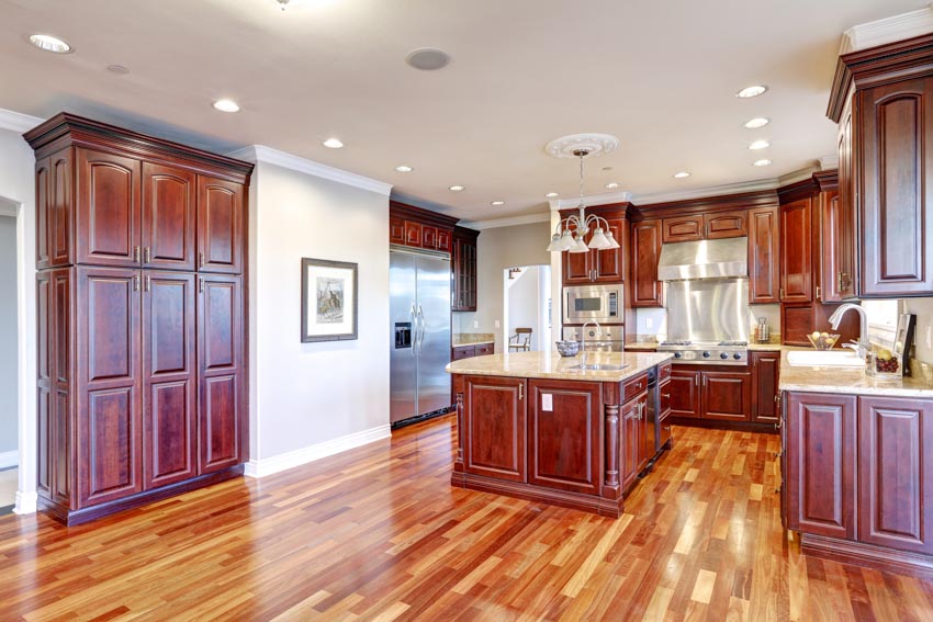 Spacious kitchen with stained cabinets, wood floors, island, countertops, and windows