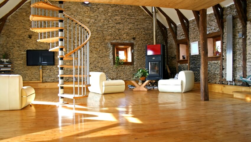 Spacious living room with stone walls, spiral stairs, uneven floor, and vaulted ceiling