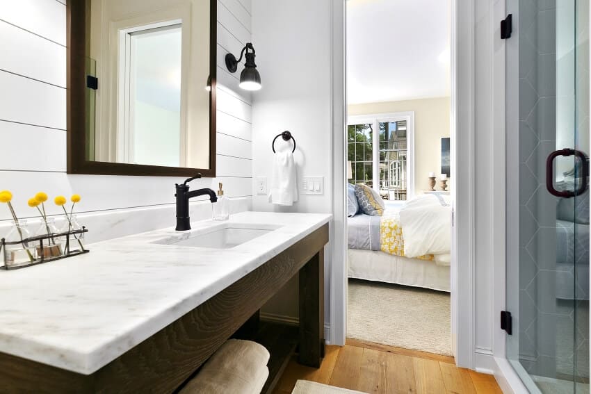 Square mirror and sconce lights on a shiplap wall in bathroom with open storage shelves