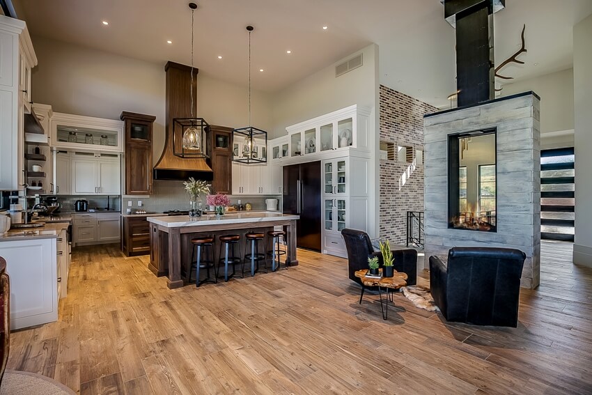 Kitchen with reclaimed engineered wood flooring, pendant lights and two black armchairs