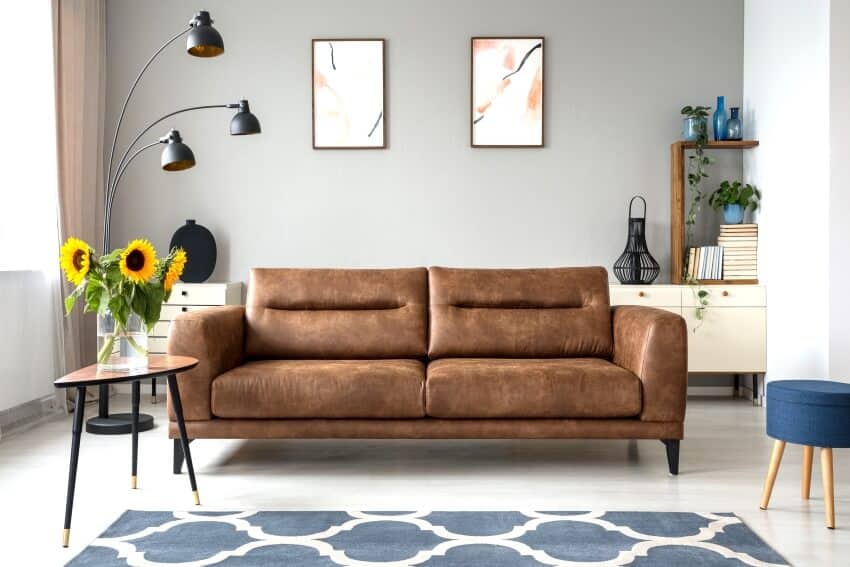 Sunflowers on wooden table next to leather sofa in room with artwork