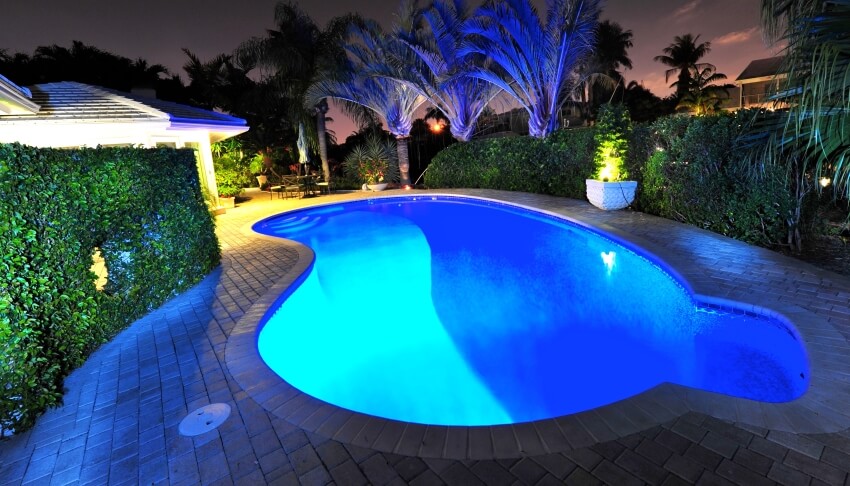Swimming pool at night with LED lights and natural stone slab on the side