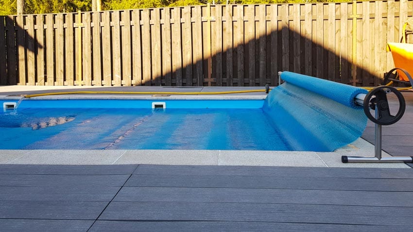 Swimming pool with fence near it and manual cover