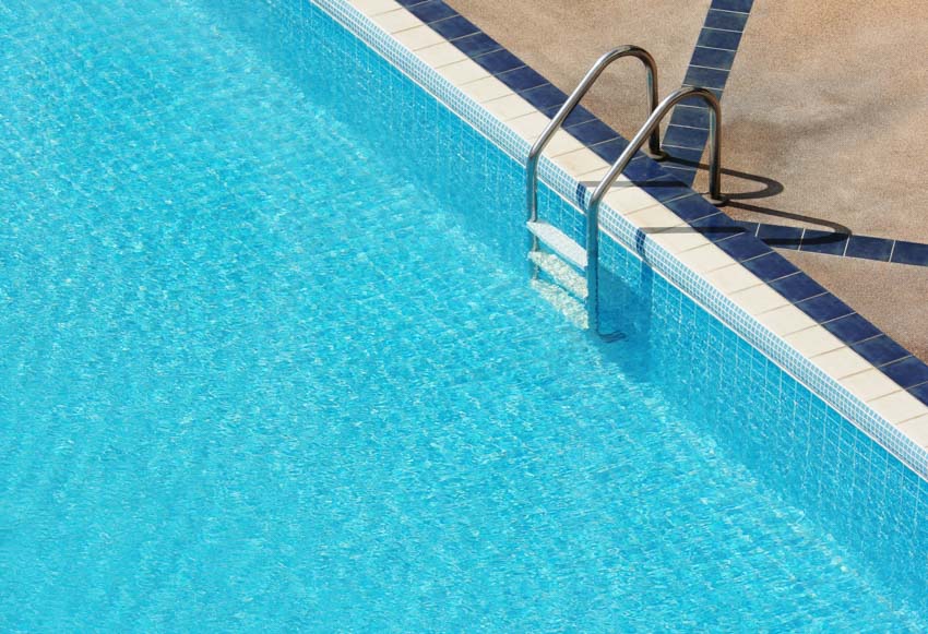 Swimming pool with metal ladder, coping, and liner