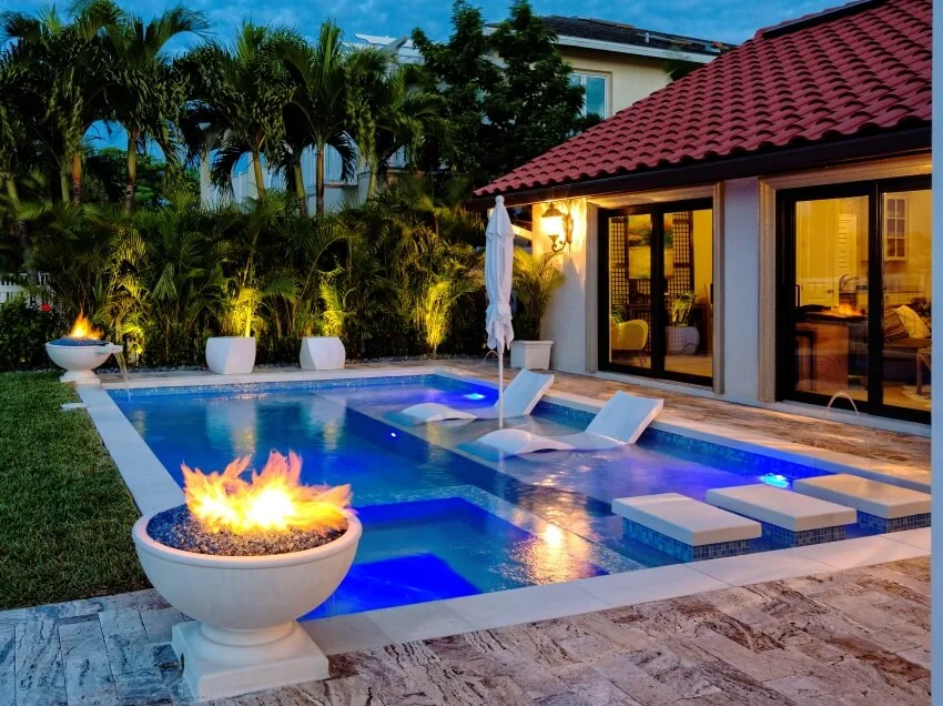 Swimming pool with sun loungers LED lights and fire pits on the corner