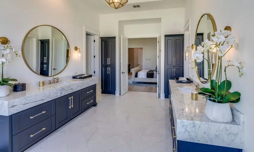 Symmetrical vanity areas with marble countertops and blue cabinets in master bathroom