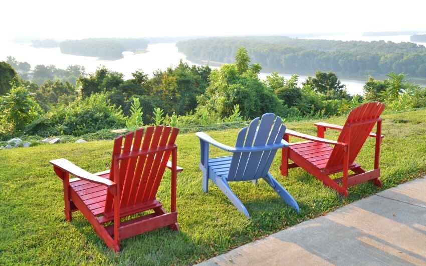 Three adirondack chairs overlooking river and landscape