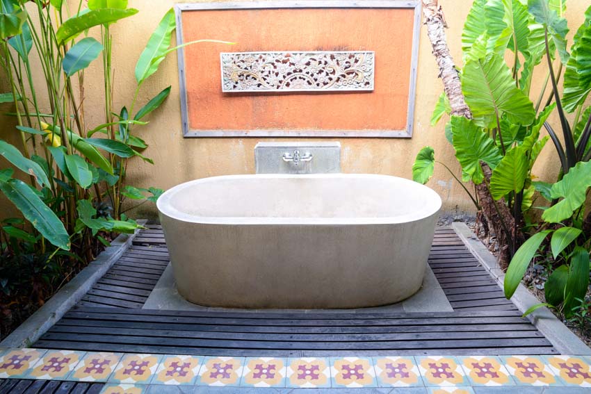 Tropical outdoor bath with tub, ornate, wall flooring, and plants