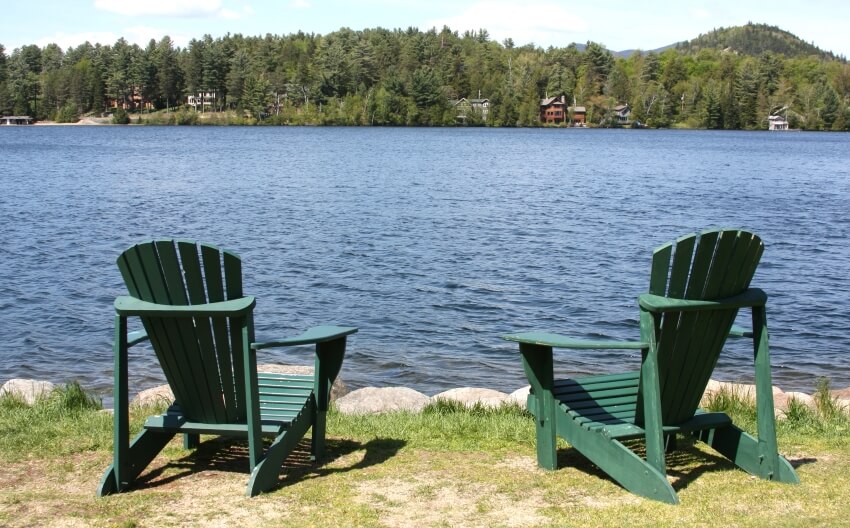 Two green adirondack chair by lake side