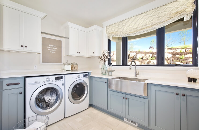 Utility room with stainless steel basin sink, grey and white cabinets, and washing machine and dryer