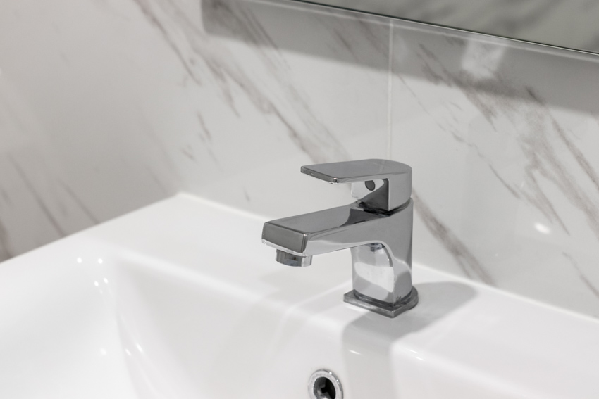 Vanity area with sink, bathroom faucet, and marble backsplash