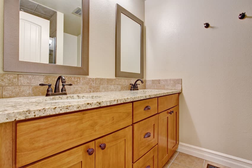Vanity with honey oak bathroom cabinets, countertop, mirrors, and faucets