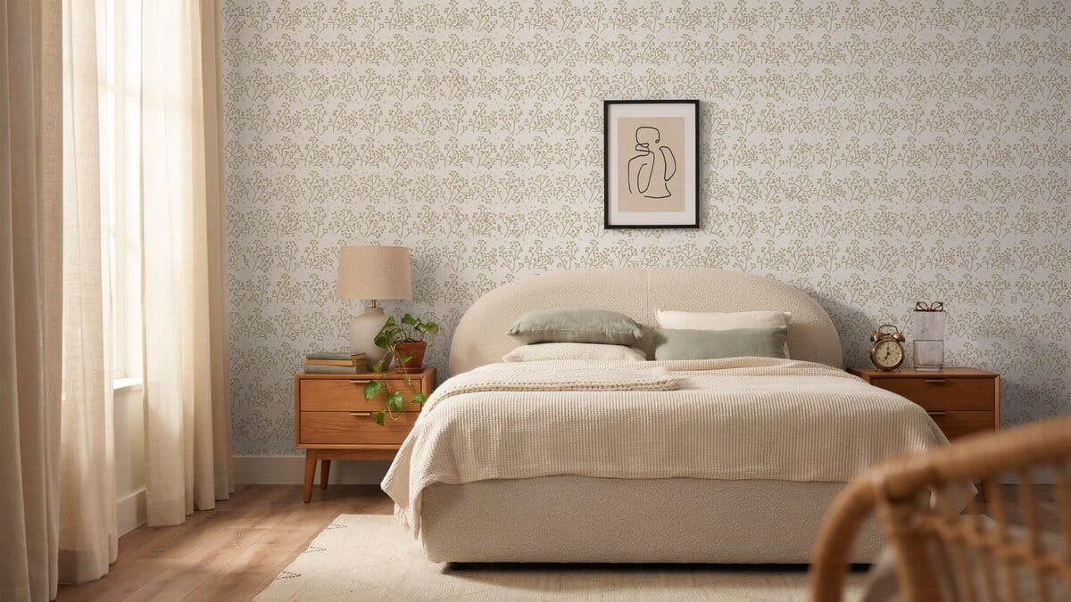 Neutral bedroom with subtle patterned vinyl wallpaper, upholstered bed, and framed art