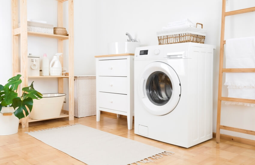 Washing machine in vintage laundry room interior with wooden furniture and portable utility sink