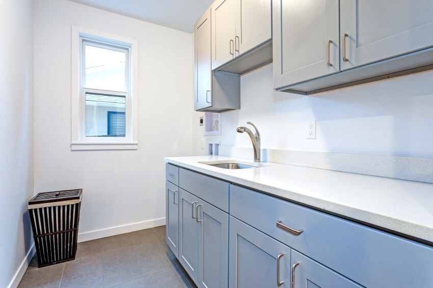 Room with white Shaker cabinets and black laundry basket on the floor