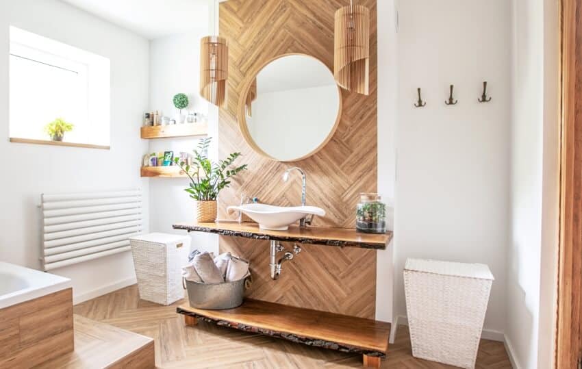 White sink on live edge wood countertop with a round mirror hanging above it in boho style bathroom