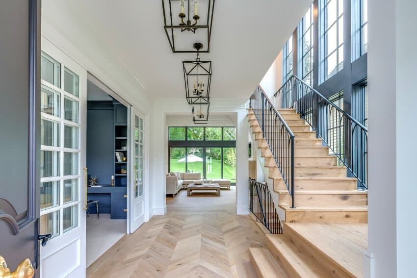 Window lined staircase, natural wood flooring, and stylish ceiling lights in an entrance hallway