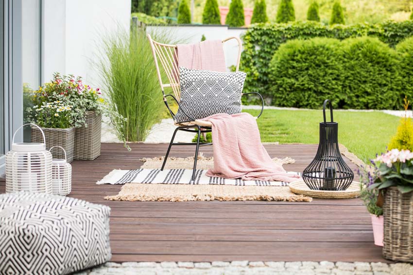 Wood deck with chair, ottoman, pillow, decor pieces, and outdoor rug