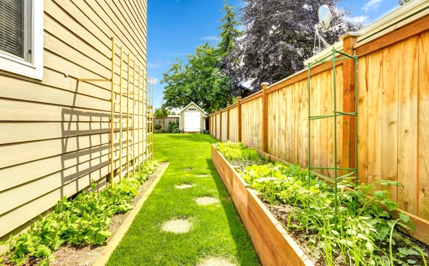 Cedar wood fenced backyard with garden bed, shed, and green lawn