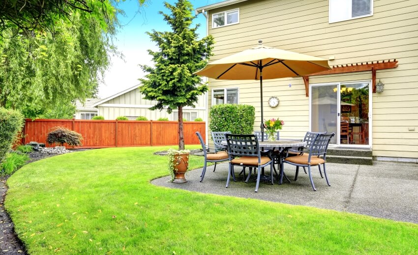 Wood fenced backyard with patio area with table set and umbrella