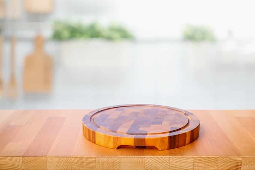 Wood table top with acacia chopping board with blur kitchen counter background
