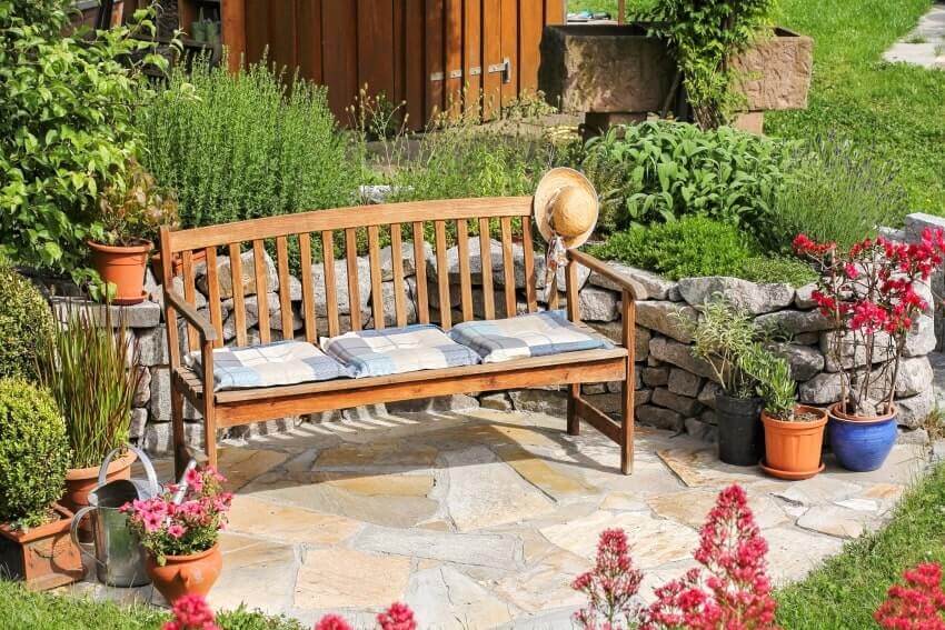 Wooden bench in the garden with stone wall