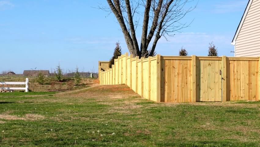 Wooden pine fence installed on uneven ground