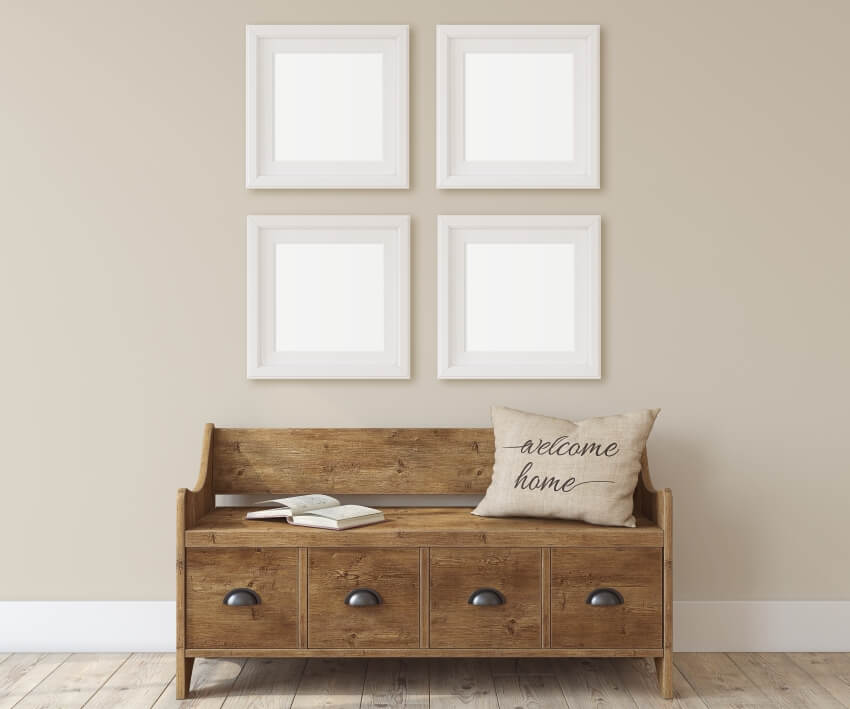 Wooden storage bench and four white square frames on the wall in the hall