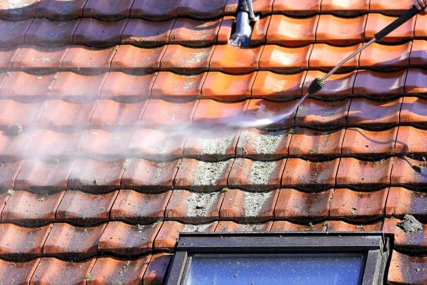 Worker cleaning the tile roof with high pressure
