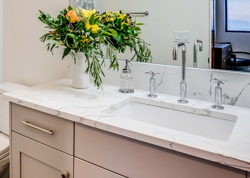 Bathroom with flowers on top of calacatta marble countertop and mirror on the wall