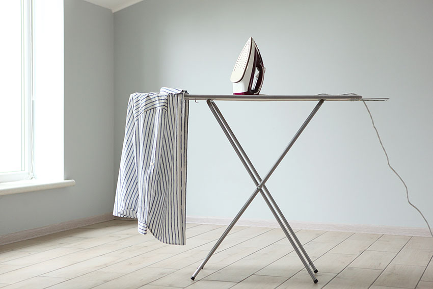 Ironing board in an empty room with gray paint