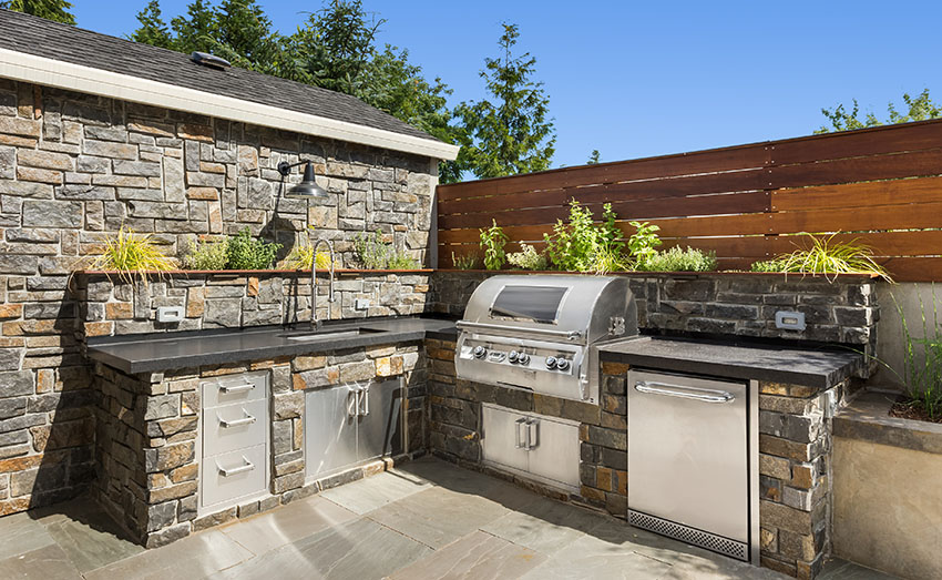 L shaped outdoor kitchen with built in stainless grill stone cladding tiles