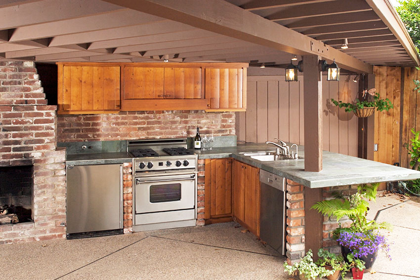 Outdoor kitchen with brick fireplace and brick walls rustic cabinet granite countertop