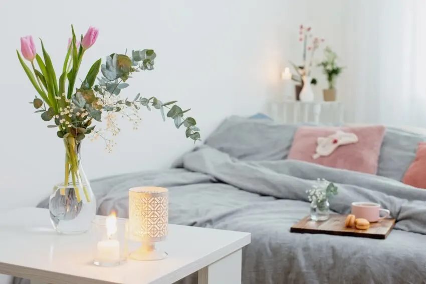A cozy bedroom with flowers, tea light wax warmer and cup of tea