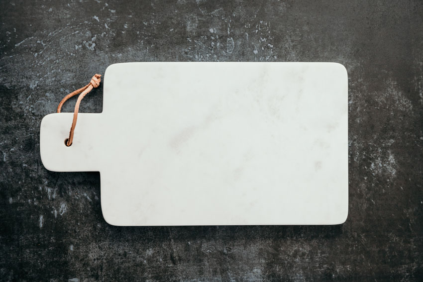 A marble cutting board on too of a kitchen surface