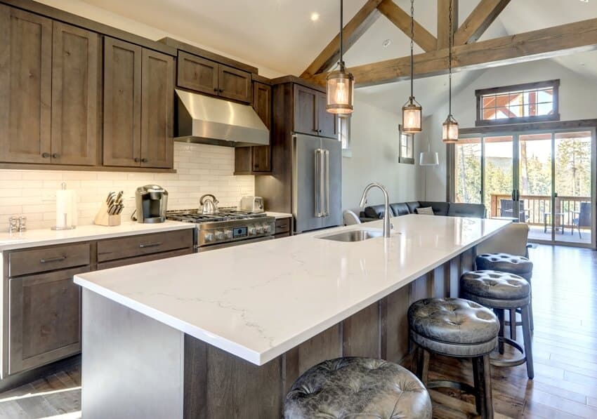 Kitchen with vaulted ceiling, wooden beams and long island with calacatta countertop