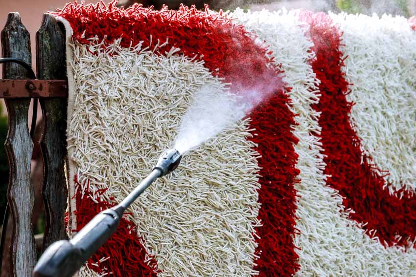 An outdoor rug hanged and cleaned by a pressure washer