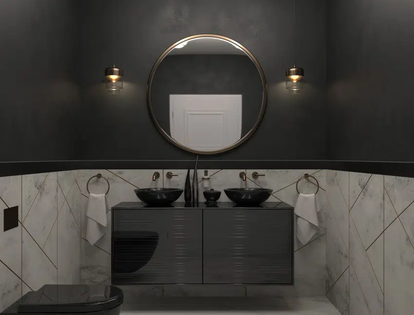 Bathroom with black countertop, dual sinks, mirror, wall-mounted lights, and toilet