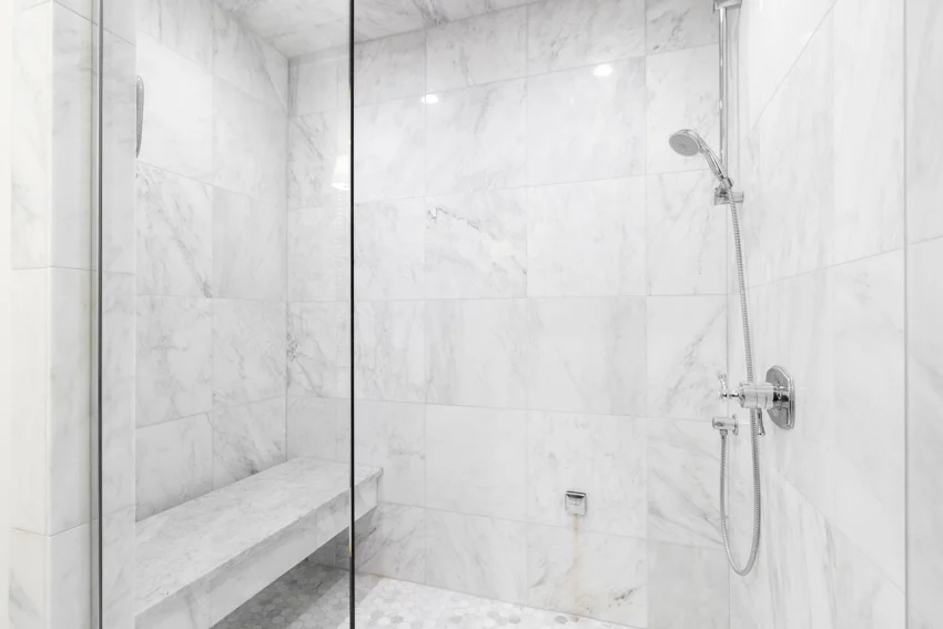 Bathroom with Carrara marble shower, bench, glass divider, and shower head