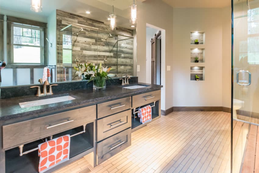 Bathroom with drawers, wood floors, black granite countertop, drawers, sink, and glass door