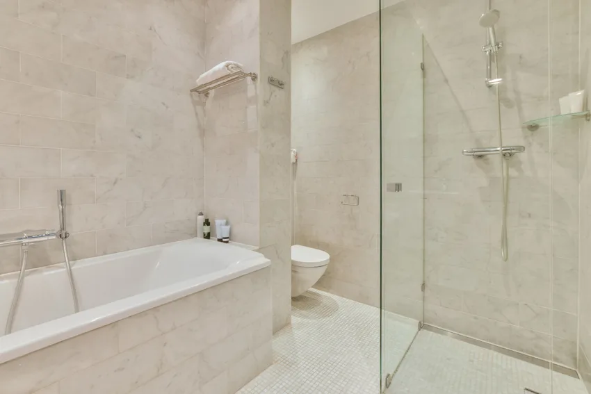 Bathroom with glass divider, bathtub, shower area, Carrara marble wall, and tile flooring