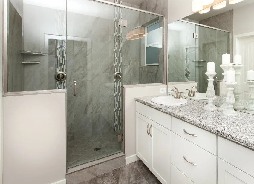Bathroom with granite countertop, white cabinets and marble shower walls and floors