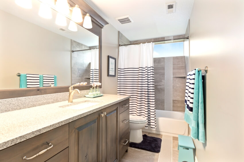 Bathroom with granite countertops, sconce light, and shower curtain in a single rod