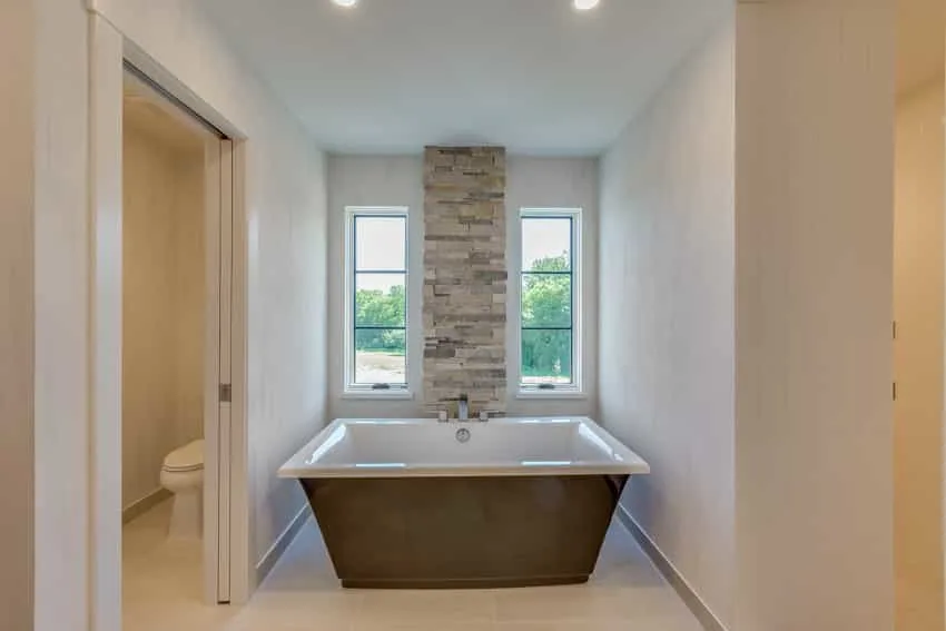 Bathroom with limestone floor, walls, bathtub, and windows