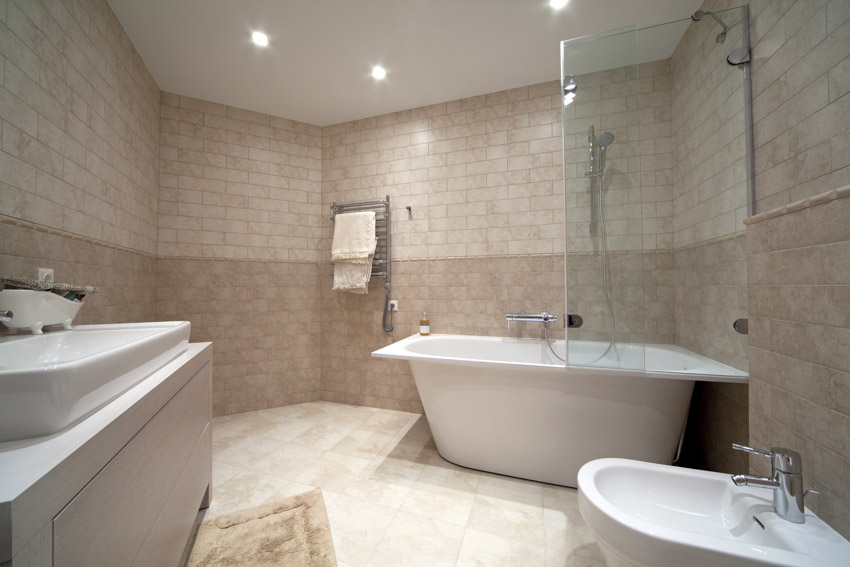 Bathroom with limestone tiles, tub, sink, and bidet