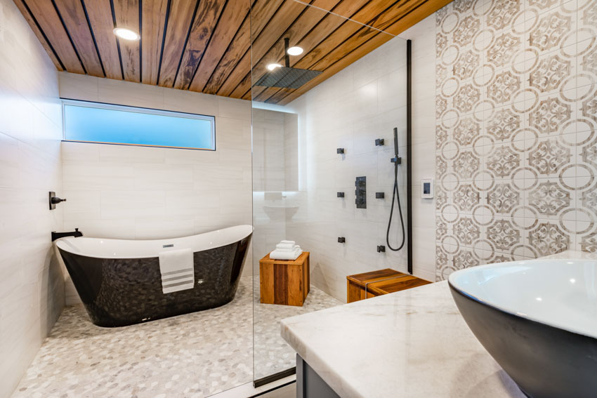 Bathroom with walk in shower, tub, tile accent wall, wood ceiling, and sink