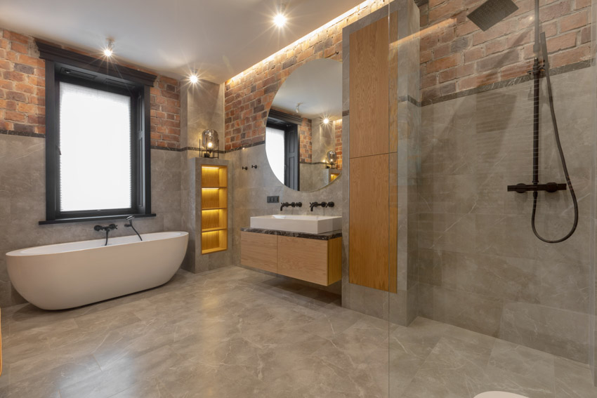 Bathroom with walk in shower, tub, window, vanity mirror, floating countertop, sink, and faucets