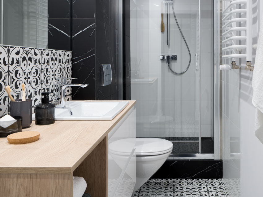 Bathroom with waterproof peel and stick floor tiles, backsplash, wood countertop, glass door, toilet, and mirror